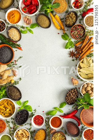 A lively frame of assorted herbs and spices on gray, highlighting the vibrant colors and flavors for cooking inspiration, top view and copy space 125798365