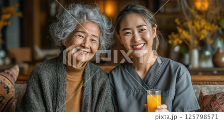 Asian senior woman, giving an orange juice to happy senior woman during home daycare, Elderly patient with healthcare 125798571