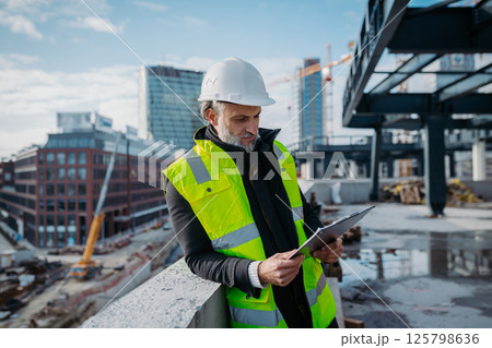 Site manager giving instructions over radio during building inspection. 125798636
