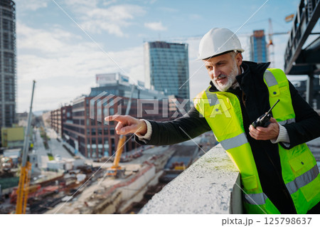 Site manager giving instructions over radio during building inspection. Site manager giving instructions over radio during building inspection. 125798637