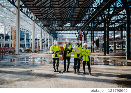 Team of engineers and construction workers inspecting building progress. Team of engineers and construction workers inspecting building progress. 125798642