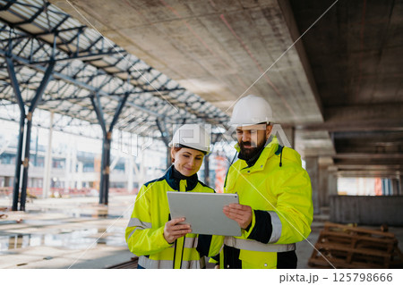 Engineers discussing construction plans using a tablet on site. Engineers discussing construction plans using a tablet on site. 125798666