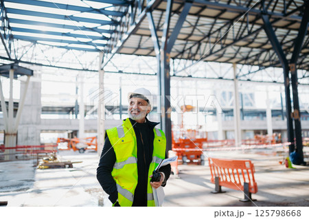 Site manager giving instructions over radio during building inspection. Site manager giving instructions over radio during building inspection. 125798668