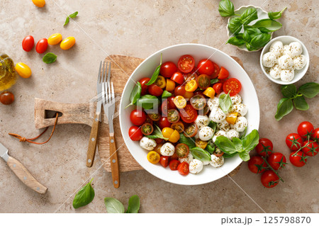 Salad with fresh cherry tomatoes, mozzarella and basil leaves, top view 125798870