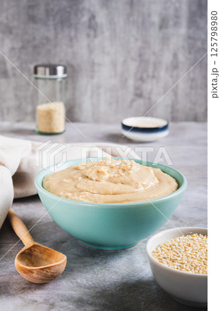Sesame tahini in a bowl and sesame seeds in a bowl on the table vertical view 125798980