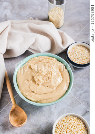 Homemade sesame tahini in bowl on grey table vertical view 125798981