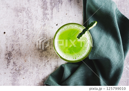 Close up of fresh cucumber juice in a glass and cucumber piece on the table top view Close up of fresh cucumber juice in a glass and cucumber piece on the table top view 125799010