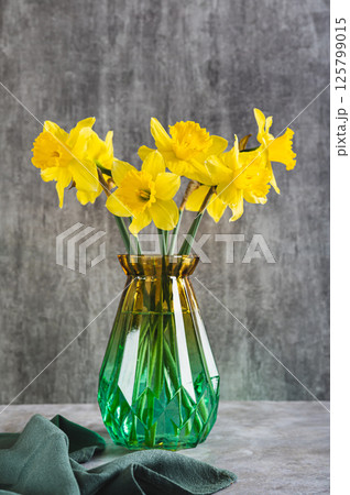Fresh spring flowers yellow daffodils in vase on grey table vertical view Fresh spring flowers yellow daffodils in vase on grey table vertical view 125799015