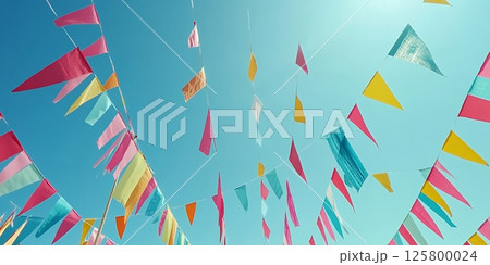 Colorful triangular flags hanging against a bright blue sky creating a festive atmosphere outdoors 125800024