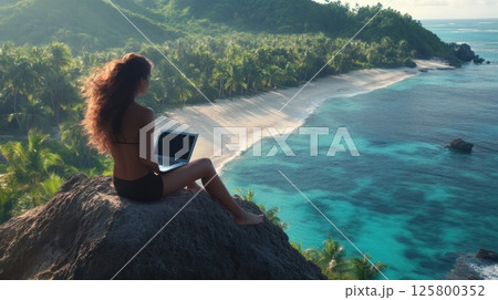 Woman working on laptop overlooking tropical beach. 125800352
