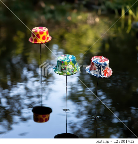 Hats afloat on water in a calm scene Hats afloat on water in a calm scene 125801412