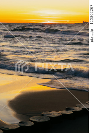 Ocean with waves, sunset sky is orange. water is choppy and waves are crashing on shore. 125802267