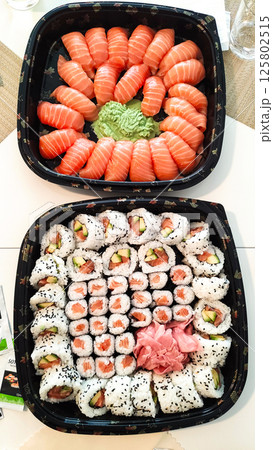 Delicious platters of fresh sushi and nigiri with wasabi and ginger displayed on table Delicious platters of fresh sushi and nigiri with wasabi and ginger displayed on table 125802515