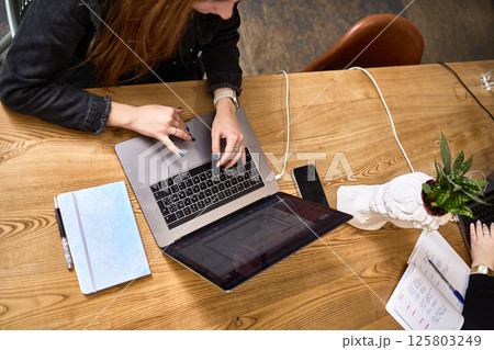 Overhead view, people working on laptops with notebooks on wooden desk, indoor office teamwork, workspace setting concept 125803249