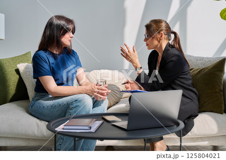 Mental therapy session, young woman patient talking to professional psychologist 125804021