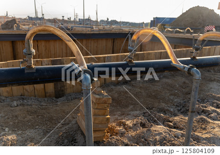 A close-up view of a series of flexible hoses connected to a pipe at a construction site 125804109