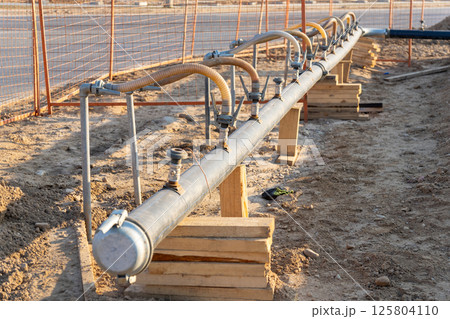 A close-up view of a series of flexible hoses connected to a pipe at a construction site 125804110