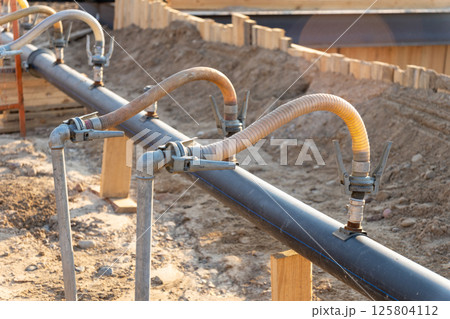A close-up view of a series of flexible hoses connected to a pipe at a construction site A close-up view of a series of flexible hoses connected to a pipe at a construction site 125804112