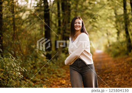 Young Woman Smiling in Autumn Forest Path Young Woman Smiling in Autumn Forest Path 125804130