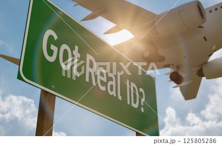 Got Real ID? Green Road Sign with Low Flying Airplane Just Above with Landing Gear Down. Got Real ID? Green Road Sign with Low Flying Airplane Just Above with Landing Gear Down. 125805286