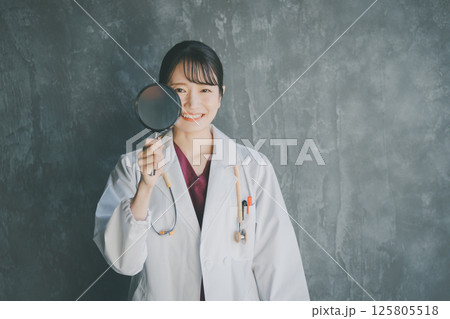 虫眼鏡を覗く女性医師 虫眼鏡を覗く女性医師 125805518
