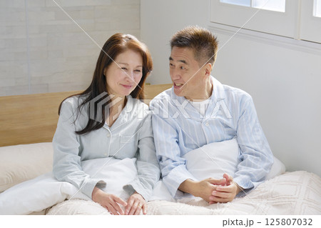 ベットの上で会話する夫婦　ポートレート 125807032