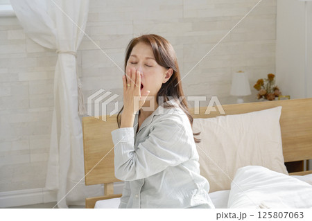 あくびをするパジャマを着た中年の女性　 125807063
