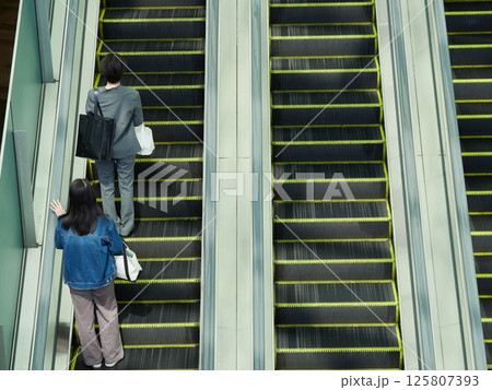 駅前の商業施設のエスカレーターに乗る若い女性買い物客の姿 駅前の商業施設のエスカレーターに乗る若い女性買い物客の姿 125807393