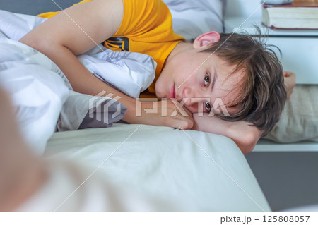 Teenager wakes up, lies in bed and looks calm, thoughtful and sad 125808057