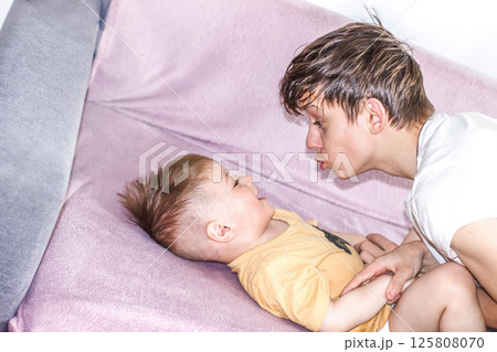 Teenage boy happily playing with his younger brother while looking after him Teenage boy happily playing with his younger brother while looking after him 125808070