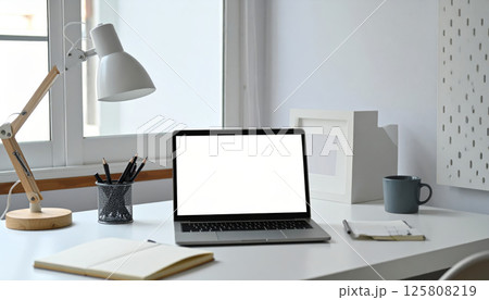 cozy organized desk featuring blank screen laptop, reading lamp, cup of coffee, and open journal, creating serene workspace atmosphere 125808219