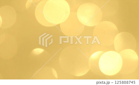 Golden shimmer creates gentle and festive atmosphere with soft bokeh circles and subtle light flares, evoking warmth and joy in any setting 125808745