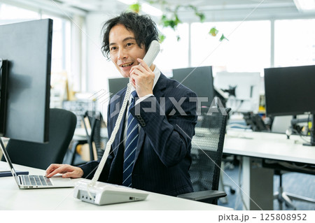 オフィスで電話する若いビジネスマン オフィスで電話する若いビジネスマン 125808952