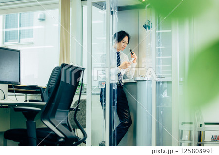 オフィスで電子タバコを吸うビジネスマン オフィスで電子タバコを吸うビジネスマン 125808991