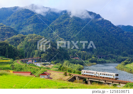 朝日を浴びながら大きなカーブを走る三江線 125810071