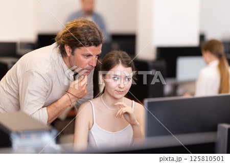 During computer lesson, male teacher helps girl student complete difficult task During computer lesson, male teacher helps girl student complete difficult task 125810501