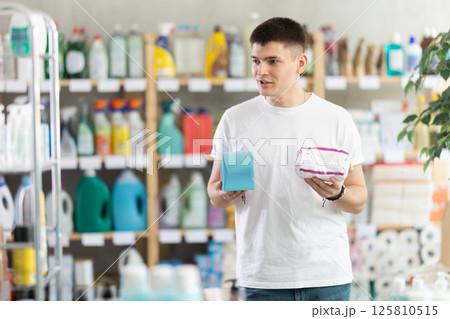 Young man chooses feminine pads in store Young man chooses feminine pads in store 125810515