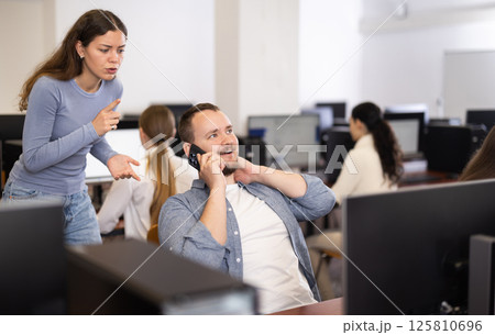Young woman makes remark to man talking on phone Young woman makes remark to man talking on phone 125810696