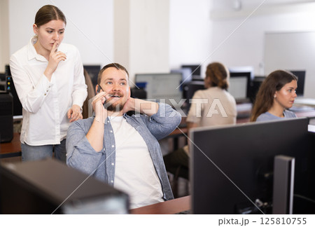 Young woman makes remark to man talking on phone 125810755