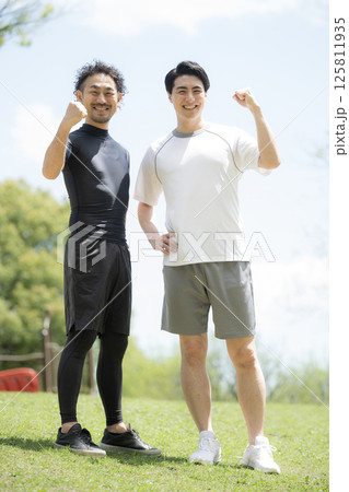 青空の中2人でスポーツする爽やかな男性2人のカメラ目線ガッツポーズ 青空の中2人でスポーツする爽やかな男性2人のカメラ目線ガッツポーズ 125811935