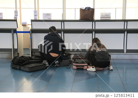 空港の出発ロビーでスーツケースの荷物を詰め替える外国人観光客 空港の出発ロビーでスーツケースの荷物を詰め替える外国人観光客 125813411