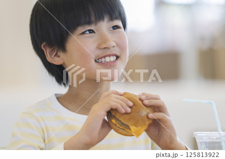 ハンバーガーを食べる笑顔の9歳の男の子 125813922