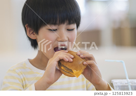 ハンバーガーを食べる9歳の男の子 ハンバーガーを食べる9歳の男の子 125813923