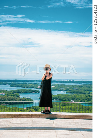 青空の下でカメラを構える女性のイメージ 125814123