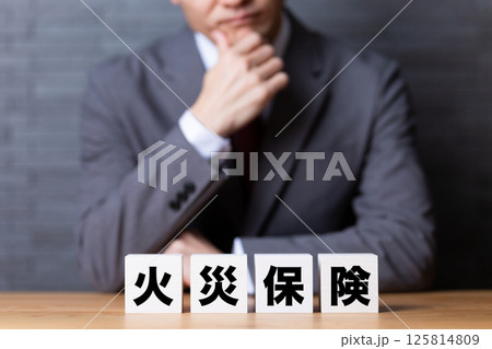 火災保険のブロックとスーツを着て悩むミドル男性ビジネスマン 火災保険のブロックとスーツを着て悩むミドル男性ビジネスマン 125814809