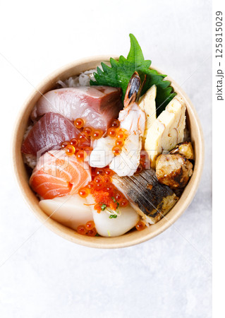 Donburi with sliced of fresh raw seafood and grilled fish on sushi rice in paper container. Healthy take away food. Donburi with sliced of fresh raw seafood and grilled fish on sushi rice in paper container. Healthy take away food. 125815029
