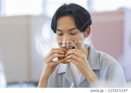 ハンバーガーを食べる30代の男性 125815147