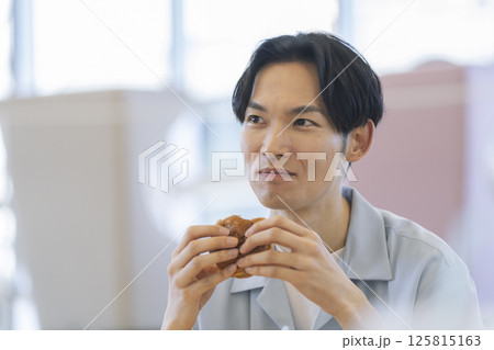 ハンバーガーを食べる30代の男性 125815163