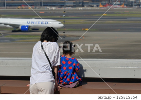 離陸する飛行機を眺める親子　羽田空港の展望デッキ 125815554