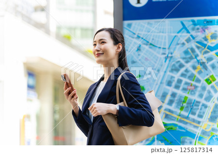 地図とスマホを見て場所を確認する女性ビジネスパーソン 125817314